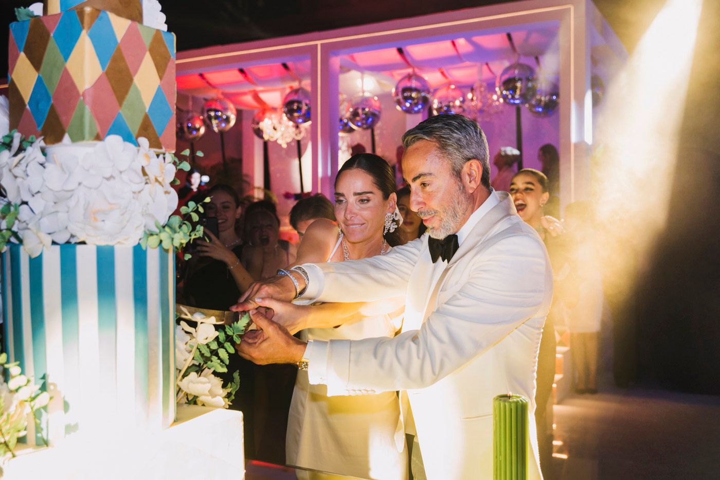 A wedding couple cuts into their modern geometric patterned cake during their reception celebration.