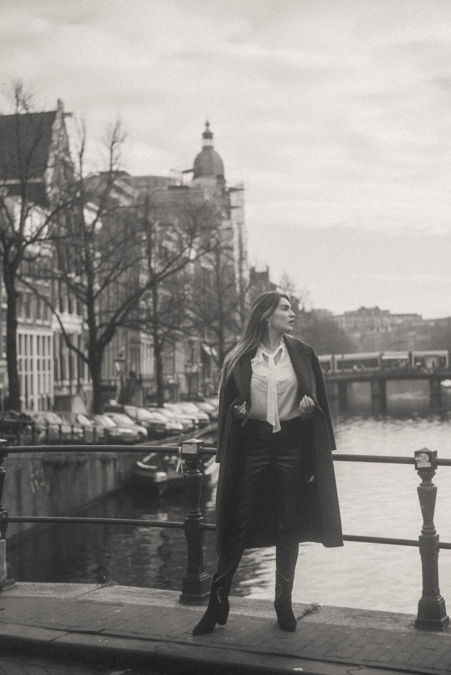 Retro-style black and white cinematic photo of a woman with Amsterdam canals in the background.