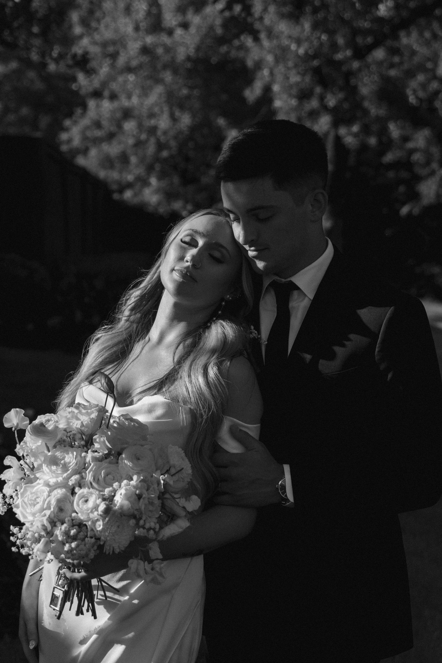 Dramatic black and white wedding portrait with white floral bouquet.