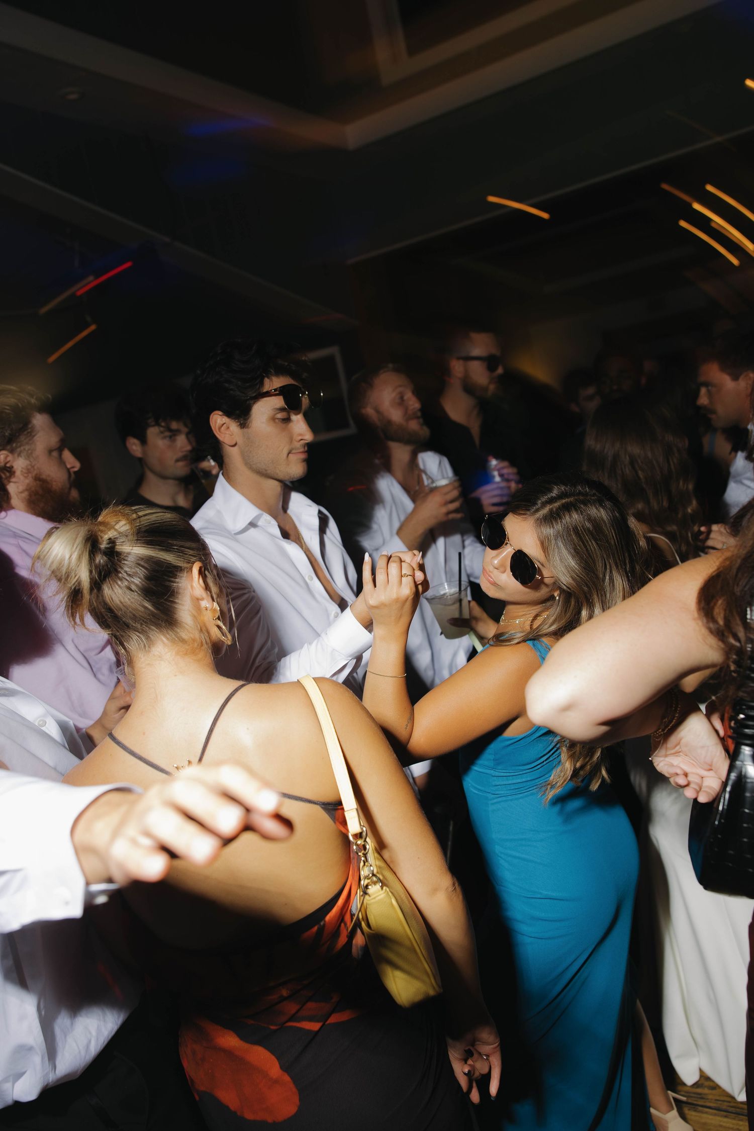A crowded nightclub dance floor with people dancing in dim lighting and festive atmosphere.