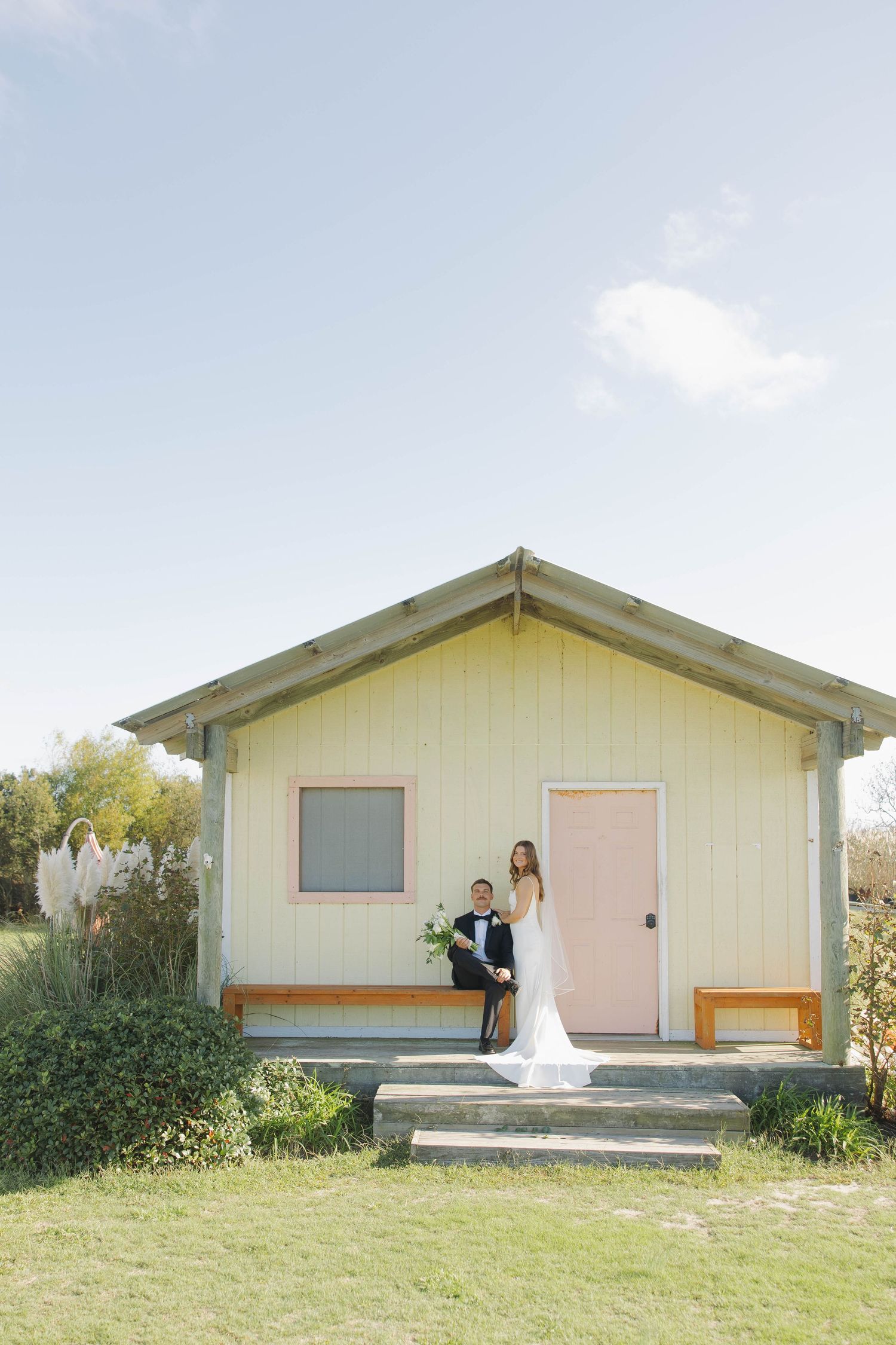 A series of five identical yellow beach cottages shown from different angles against a bright sky and grassy landscape.