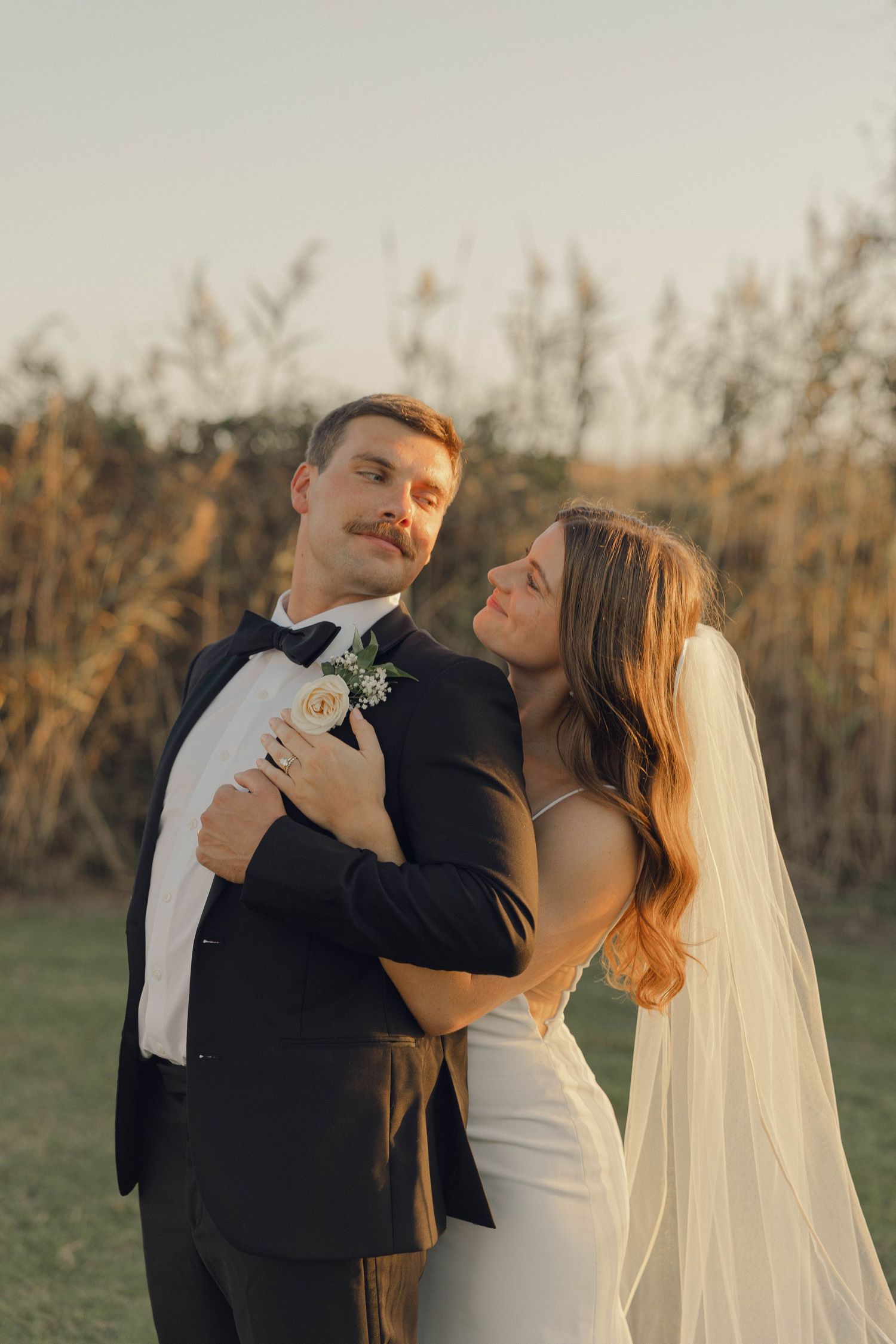 A romantic sunset wedding photo series showing a couple dancing and embracing in an outdoor field.