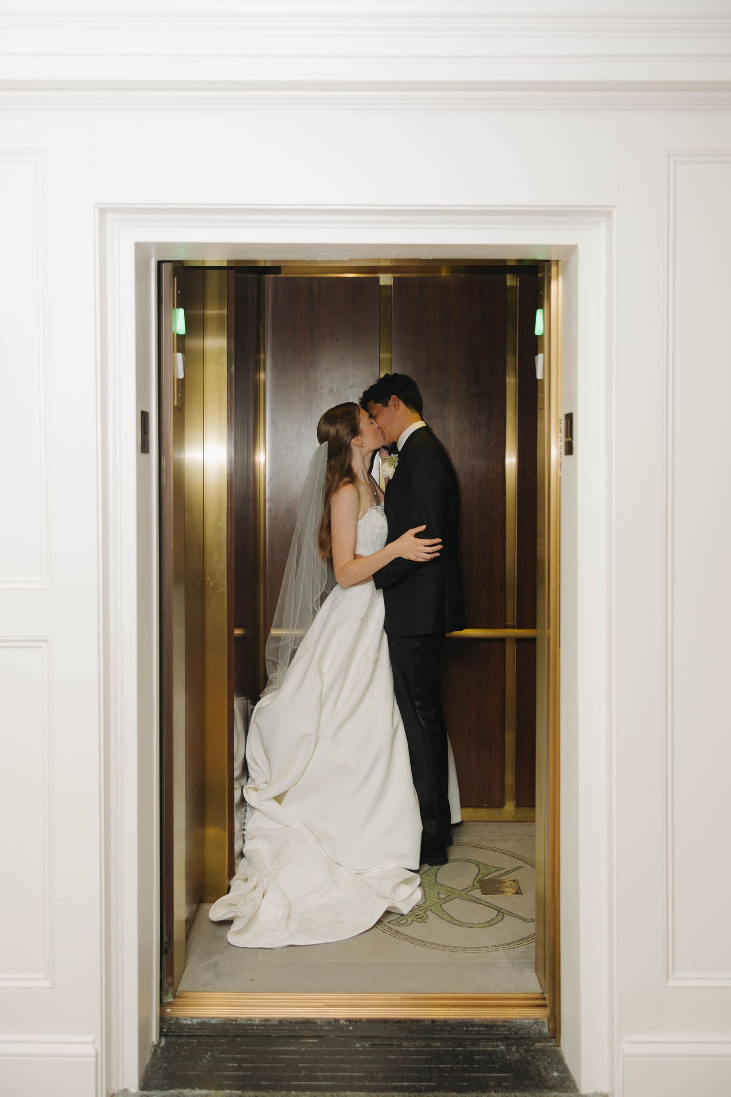 A bride and groom share an intimate moment in an elevator doorway at their wedding.