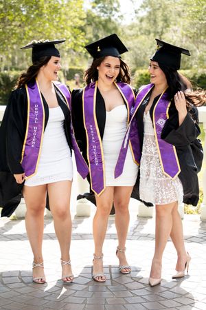 Graduates display their shoes and purple sashes in coordinated group photo.