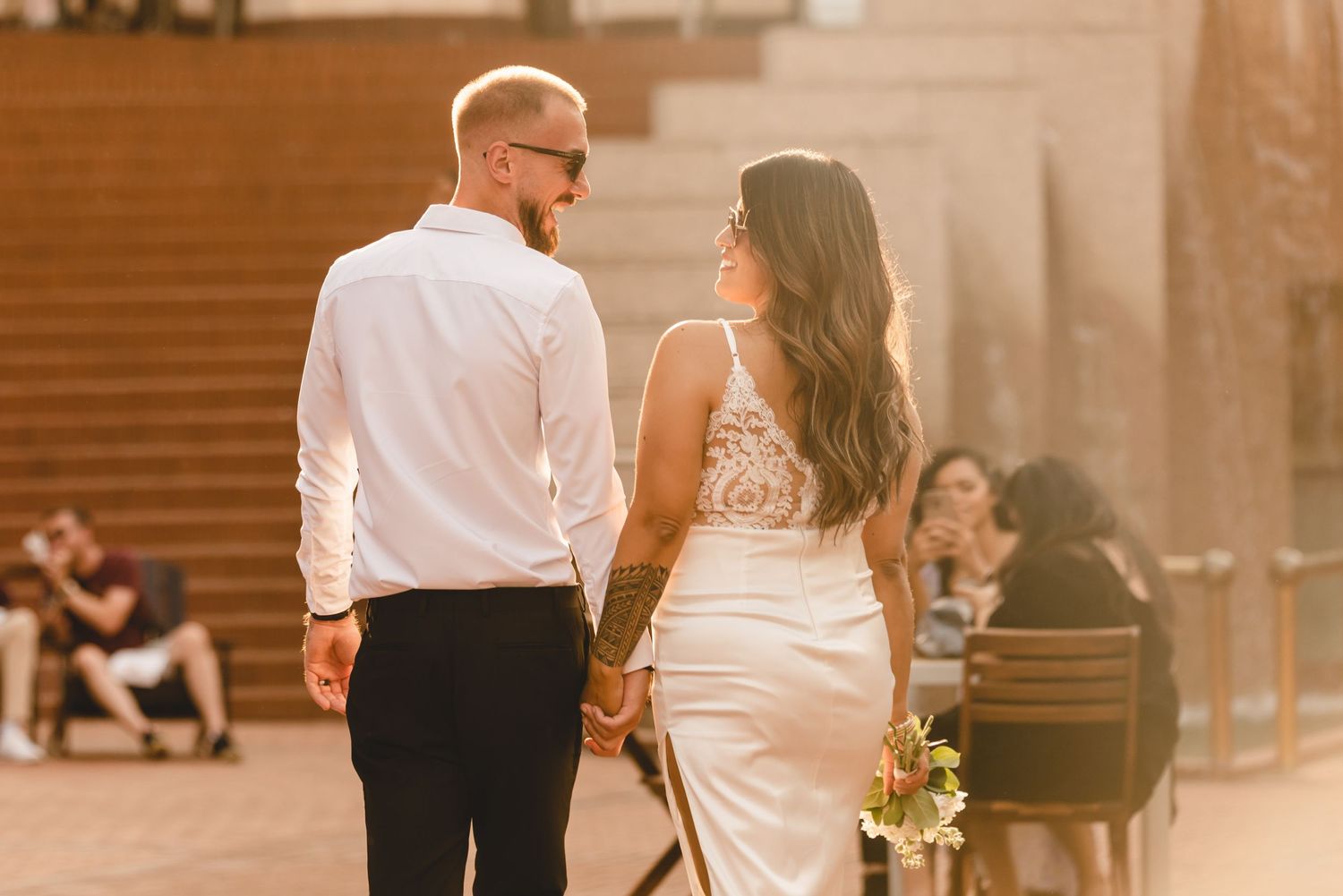 A couple shares a romantic moment at sunset on outdoor steps with warm golden lighting.