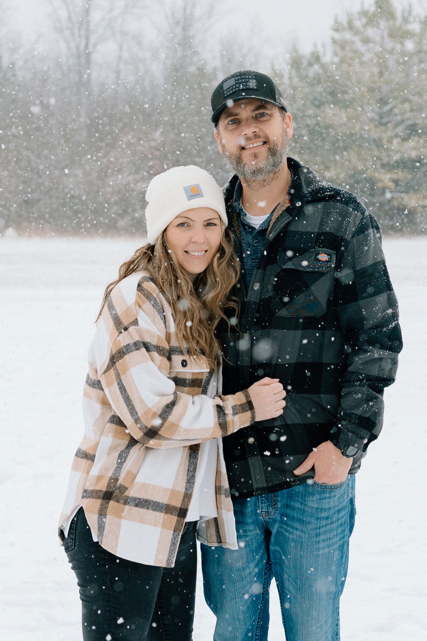Couple enjoying a romantic winter photoshoot in the snow wearing coordinated plaid and black outfits Chattanooga Family