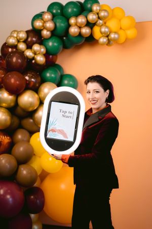 Lady holding the Roamer photo booth, smiling with joy and excitement, capturing fun moments during her event.