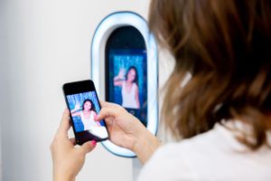 Girl looking at her phone, viewing the instant photo booth picture, showcasing how photos are instantly available on your phone.