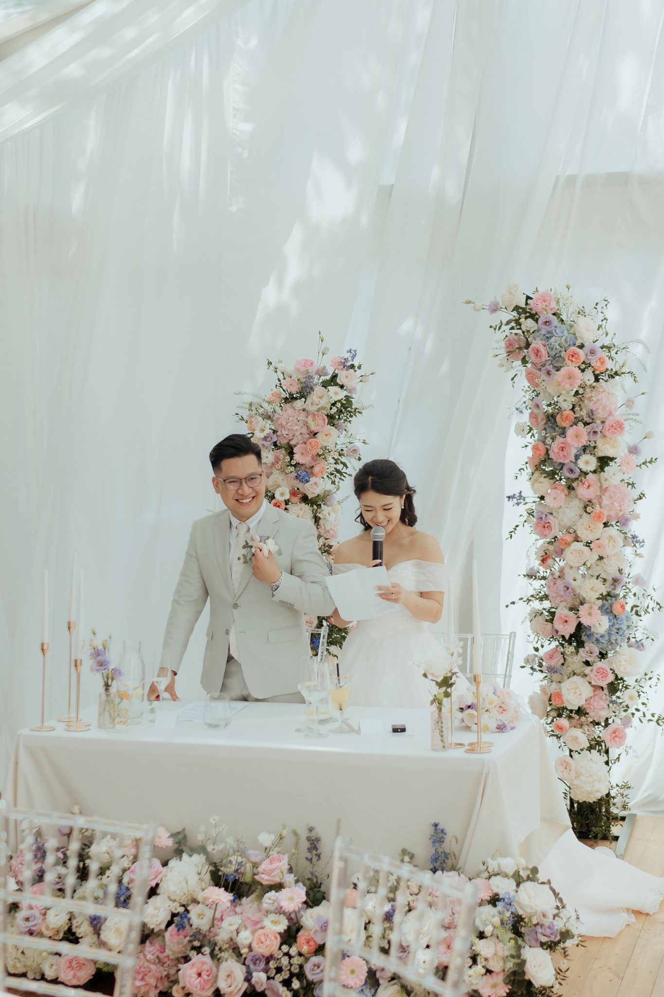 Wedding ceremony setup with floral arrangements and white draping.