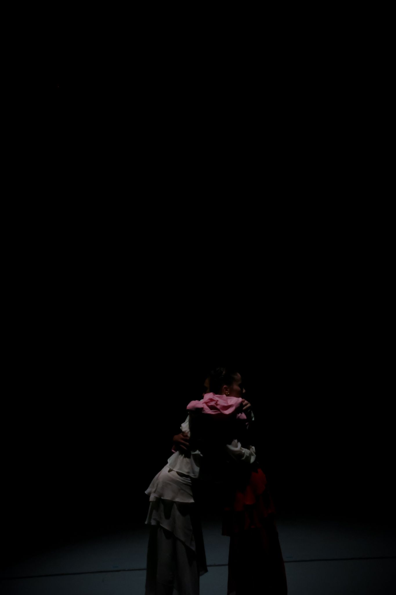 Silhouetted performers in dramatic poses on a dimly lit stage.