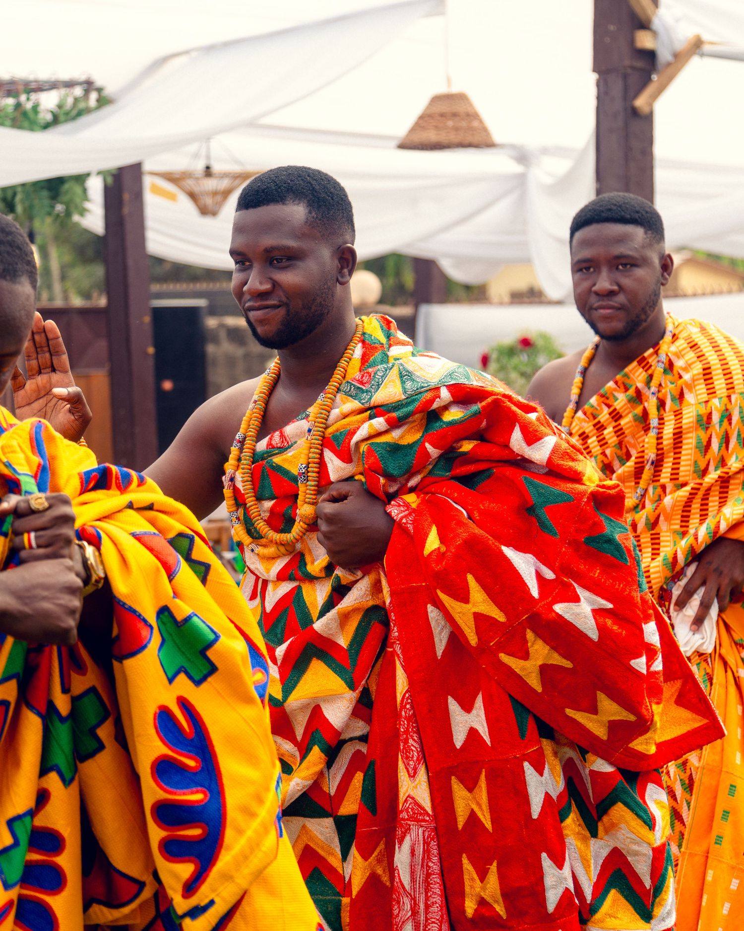 Traditional Ghanaian kente cloth in vibrant red, yellow and green patterns displayed at outdoor cultural event.