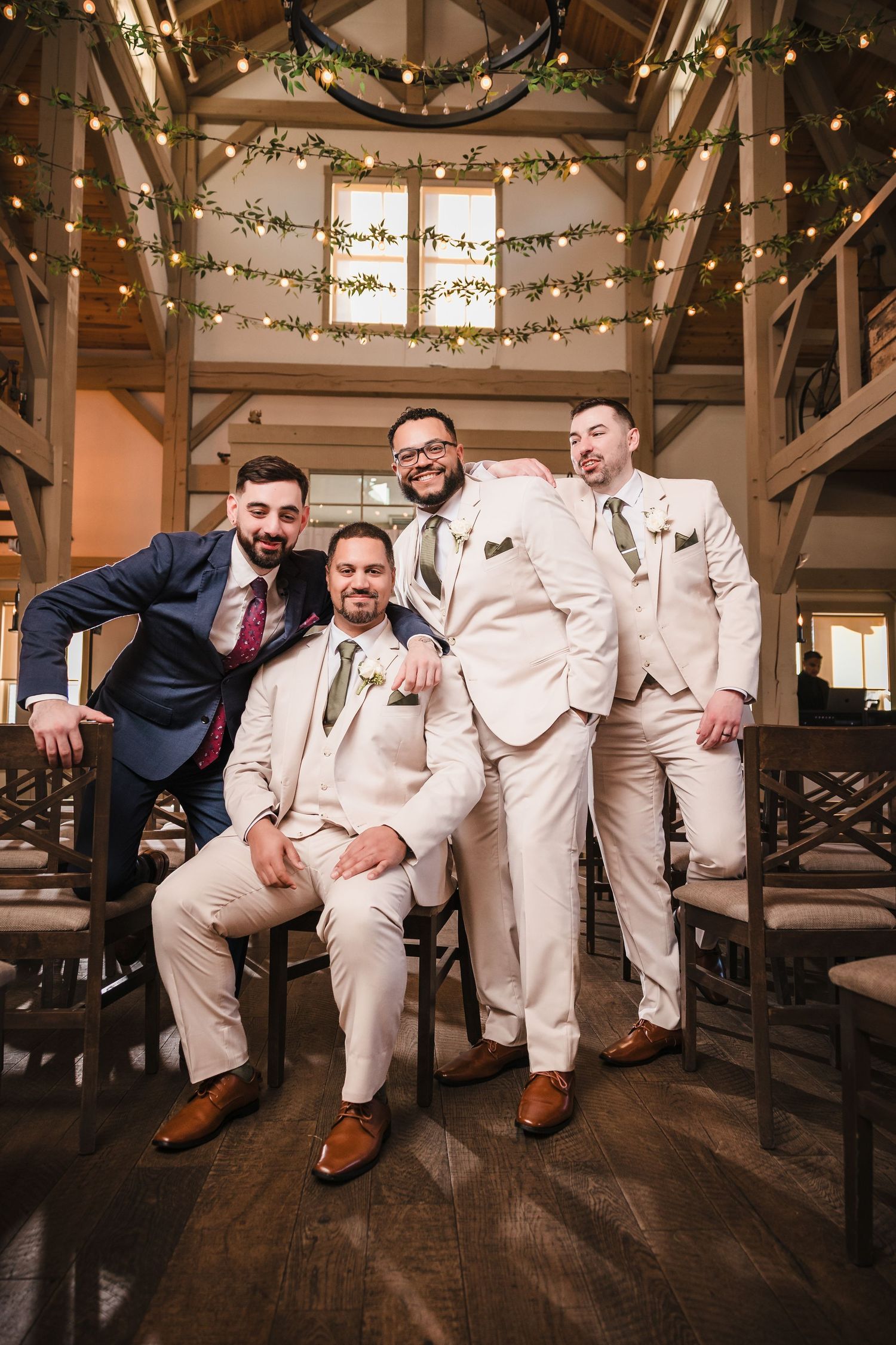 Groom and groomsmen posing together at Briar Barn Inn ceremony space with rustic wood interior and string lights