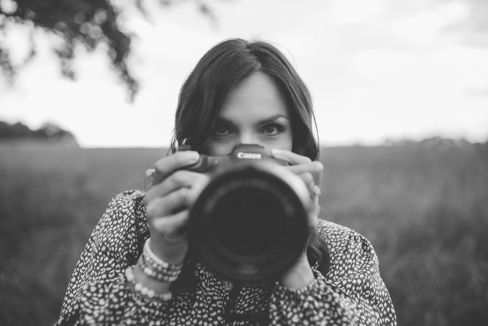 Photographer holding a camera up to take a photo in black and white.
