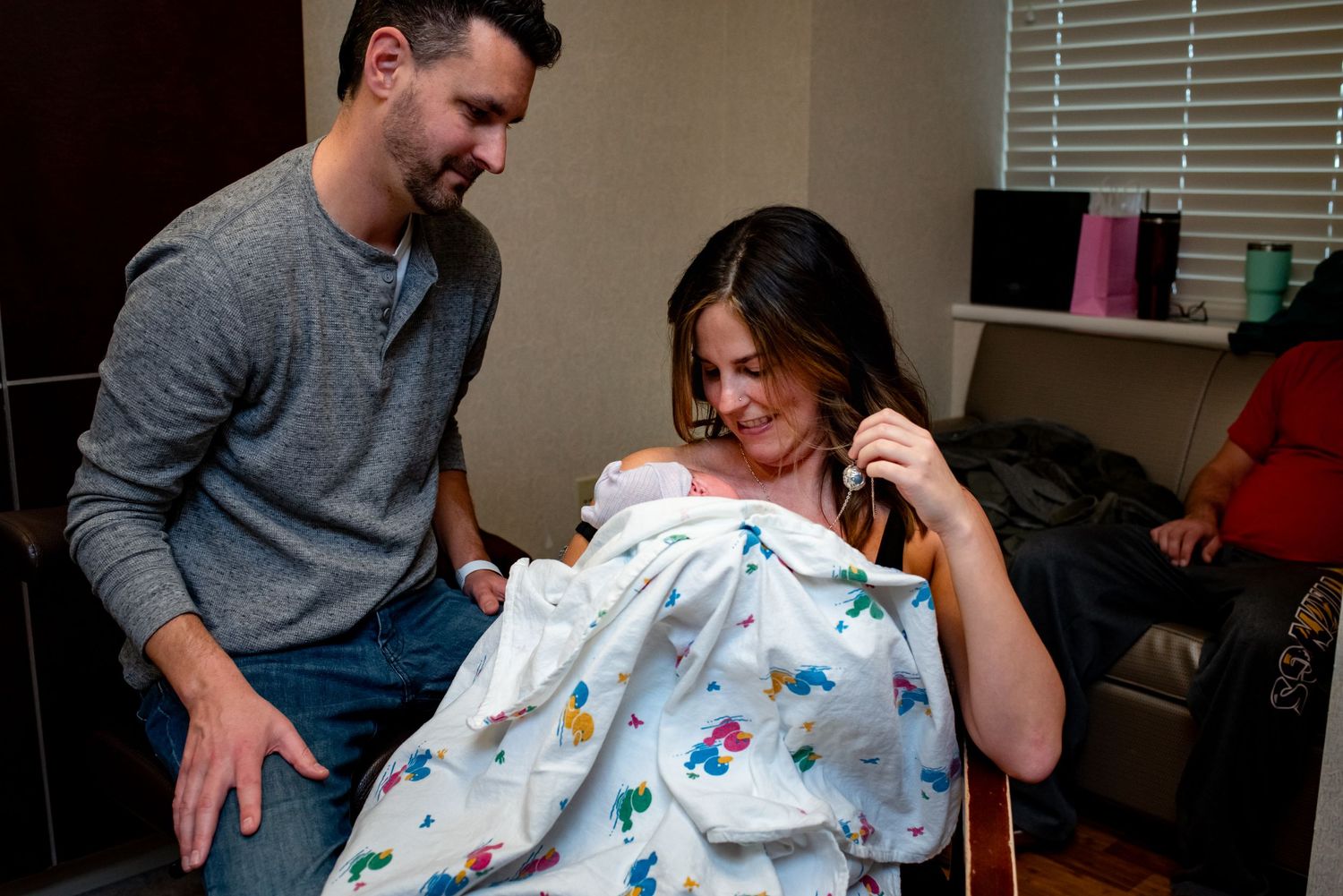 A tender hospital scene shows parents bonding with their newborn while wrapped in a butterfly-patterned blanket.