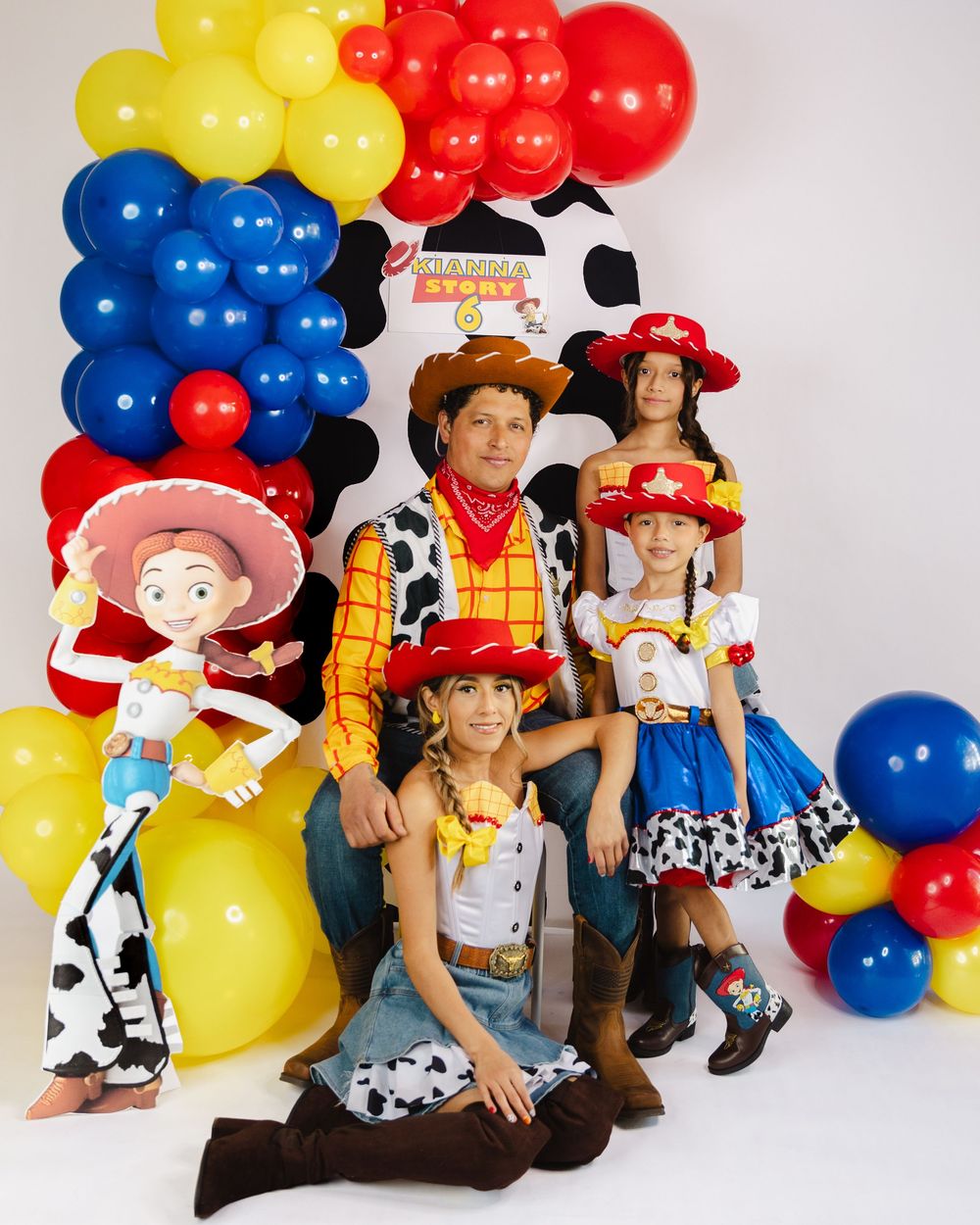 Family dressed as Toy Story characters at a themed birthday party with colorful balloons.