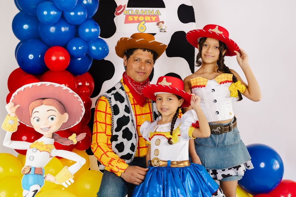 Family of four dressed in Toy Story costumes smile at a festive Toy Story themed birthday party.