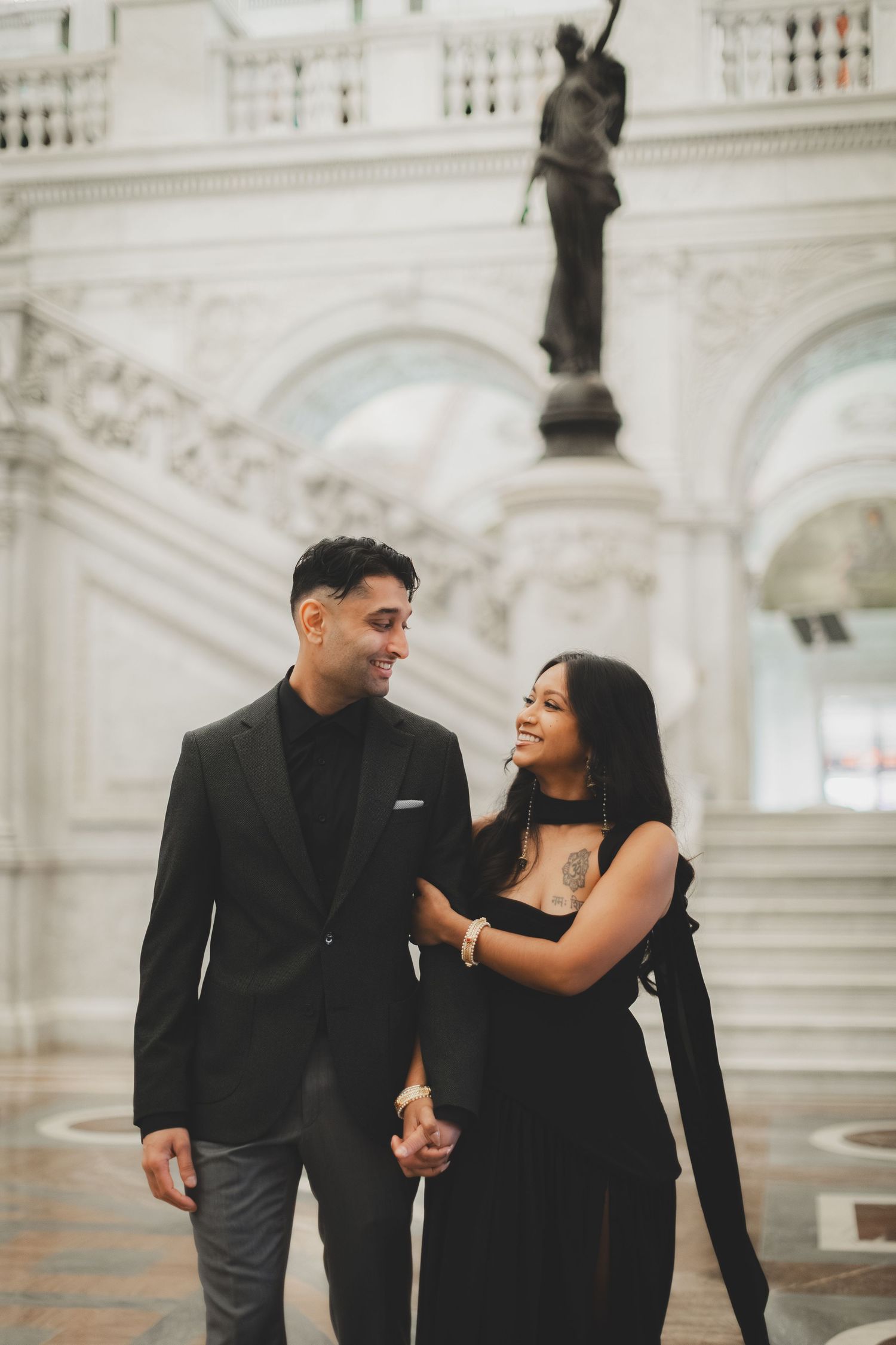 Couple in matching black outfits holding hands and smiling at each other in for a library of congress photography session