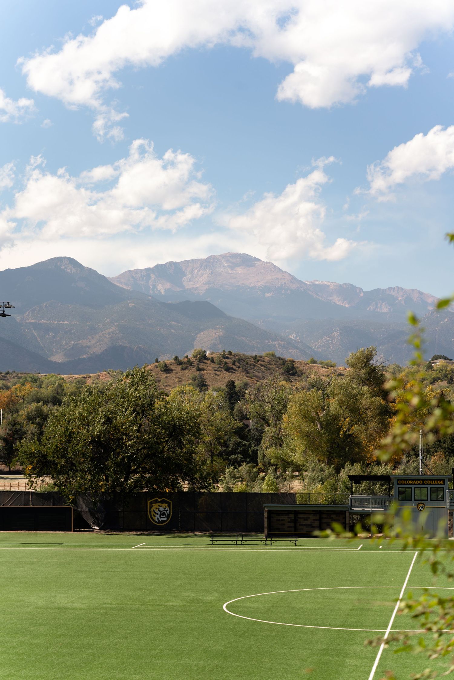 Soccer field with mountain range backdrop under blue sky.