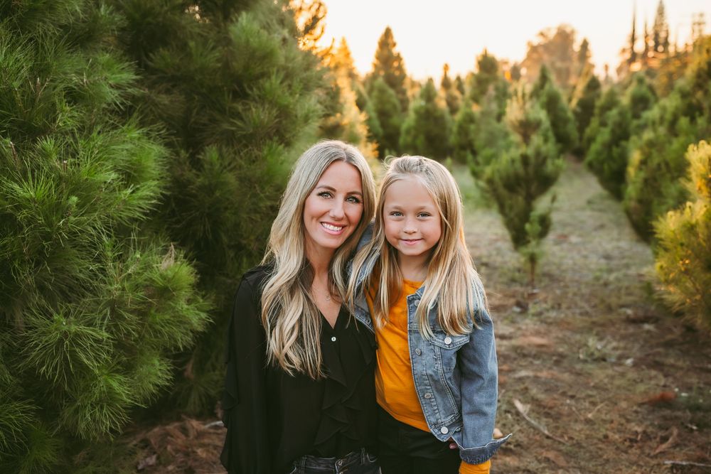 Woman and young girl smiling together at a Christmas tree farm during the holidays in mentone ca