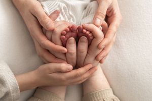Parents cradling newborn baby feet in their hands, natural newborn photoshoot Nottingham