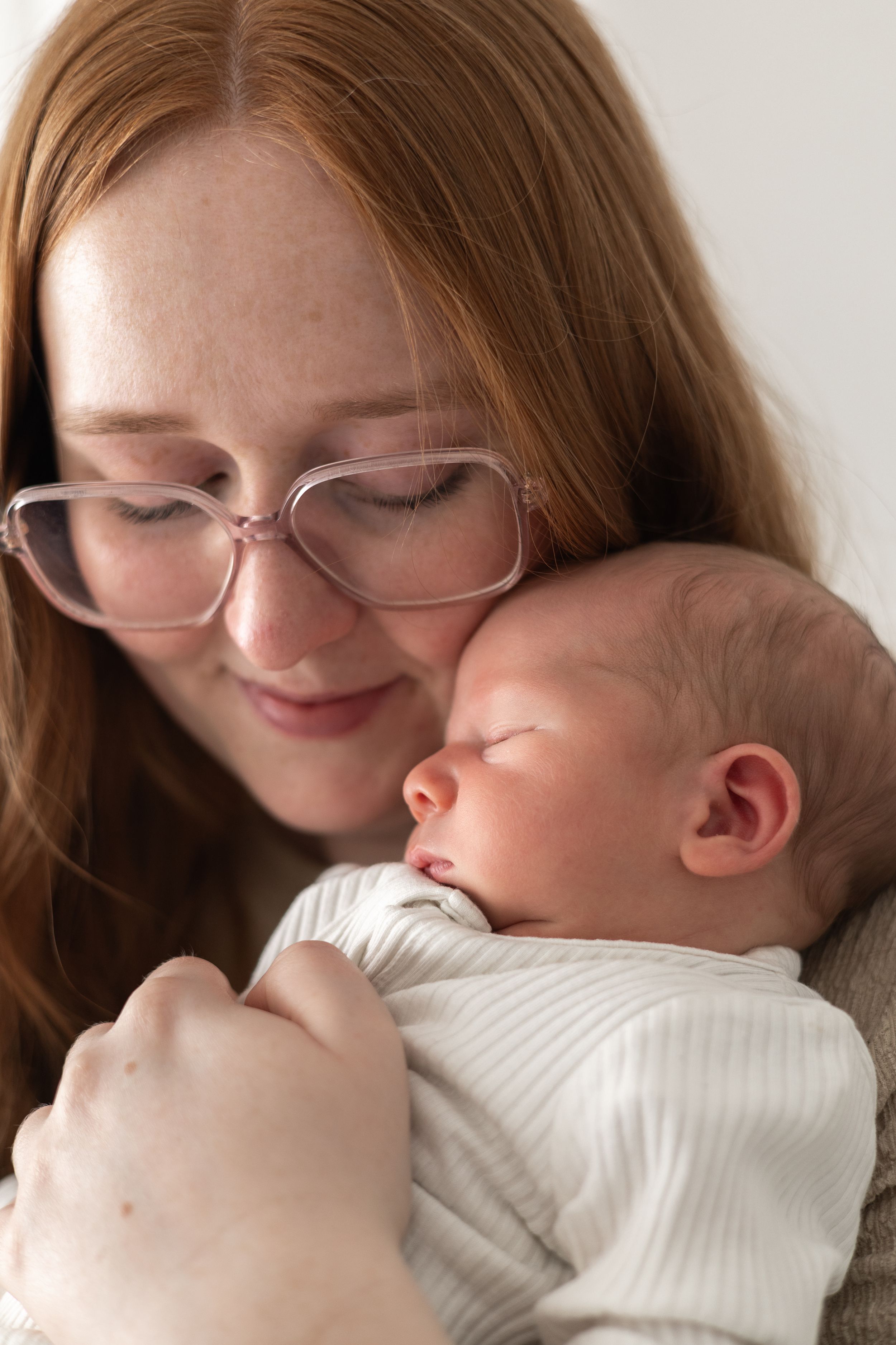 Mother tenderly holding sleeping newborn baby, newborn photoshoot Nottingham