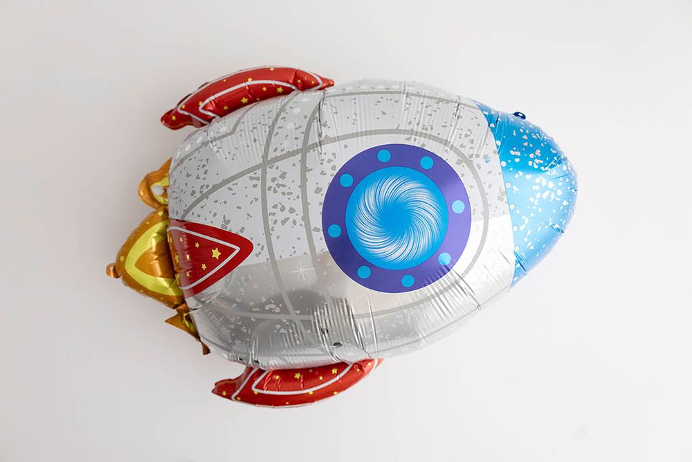 Colorful rocket ship foil balloon in silver, red, blue and gold for 1st trip around the sun birthday photoshoot.