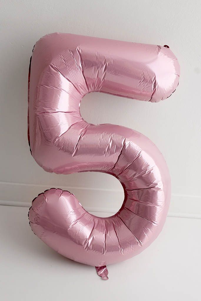 Pink number 5 foil balloon leaning against white wall for 5th birthday photographer in Temecula.