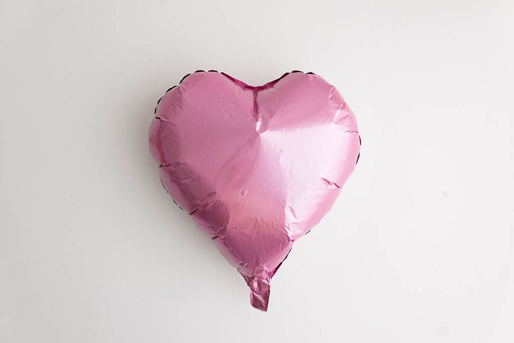 Pink heart-shaped foil balloon on white background for Valentine's Day photoshoot in Menifee area.