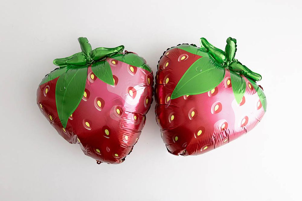 Two red strawberry shaped balloons for themed cake smash photos in Southern California.