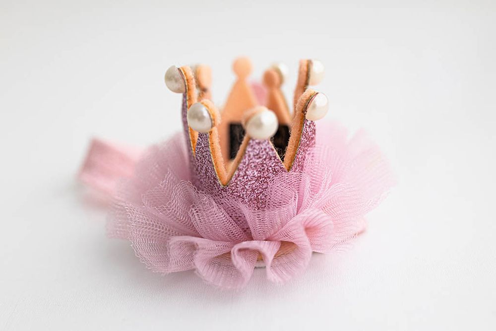 Pink glitter crown with pearl embellishments and pink tulle ruffle on elastic headband.