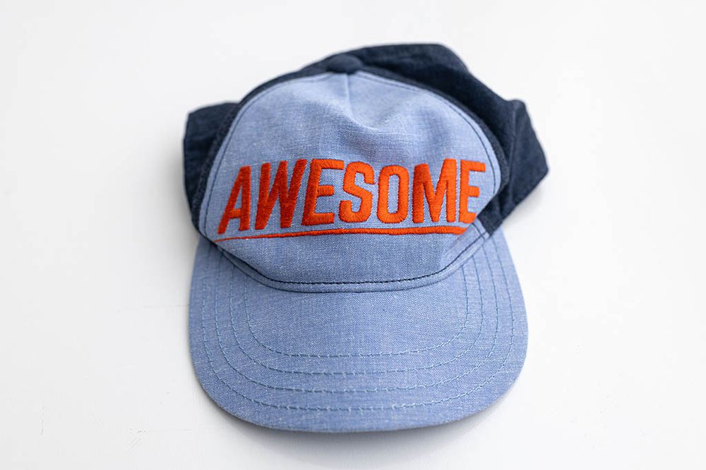 Baby boy's light blue denim snapback cap with with AWESOME printed across front.