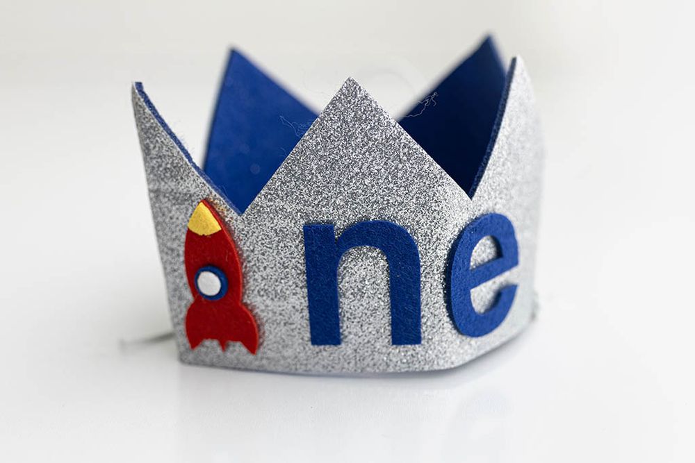 Silver glitter birthday crown with rocket ship applique spelling one, Baby Photographer in Winchester, California.