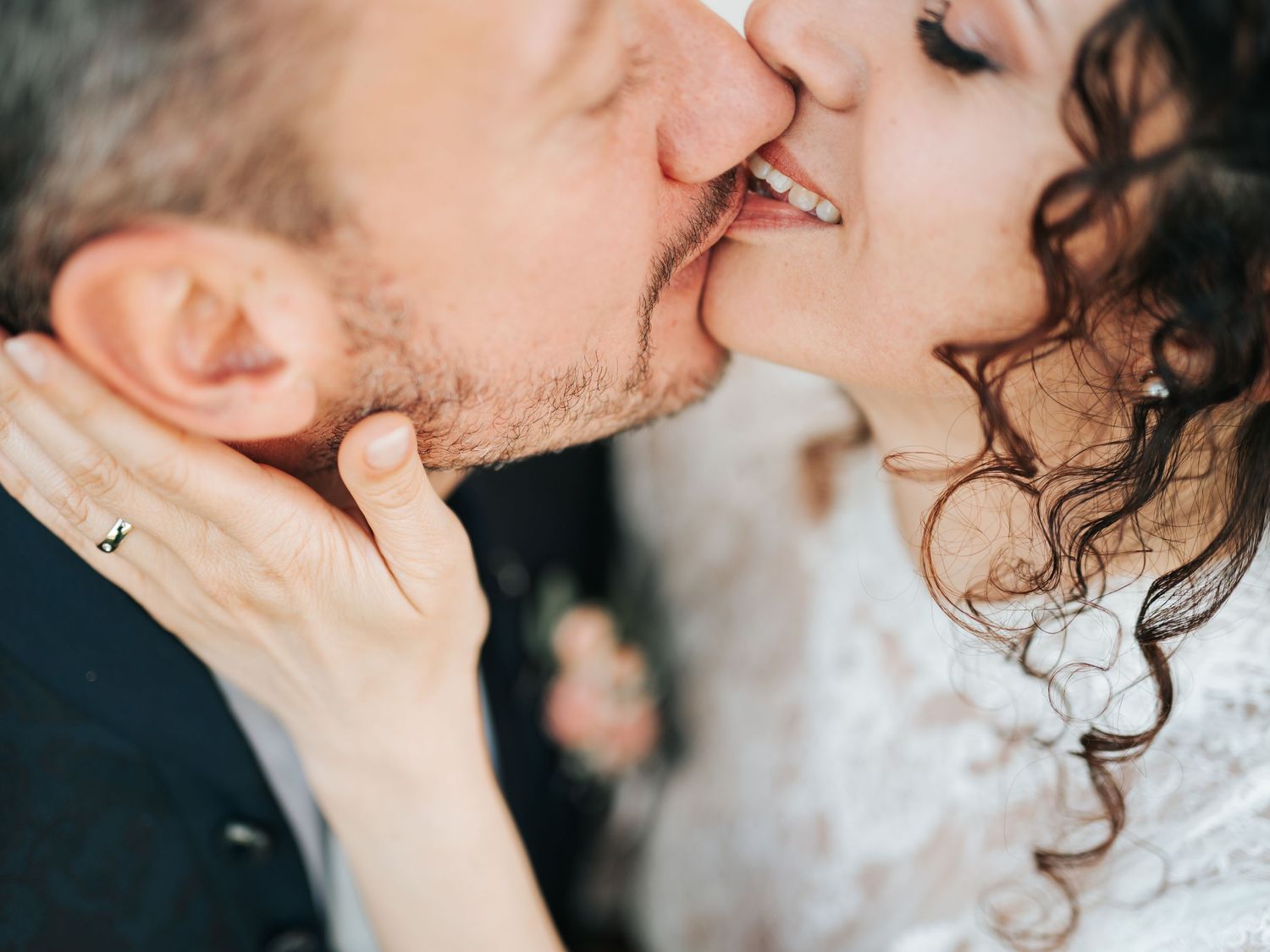 Close-up of wedding couple sharing a romantic kiss, bride wearing lace dress and groom in suit.