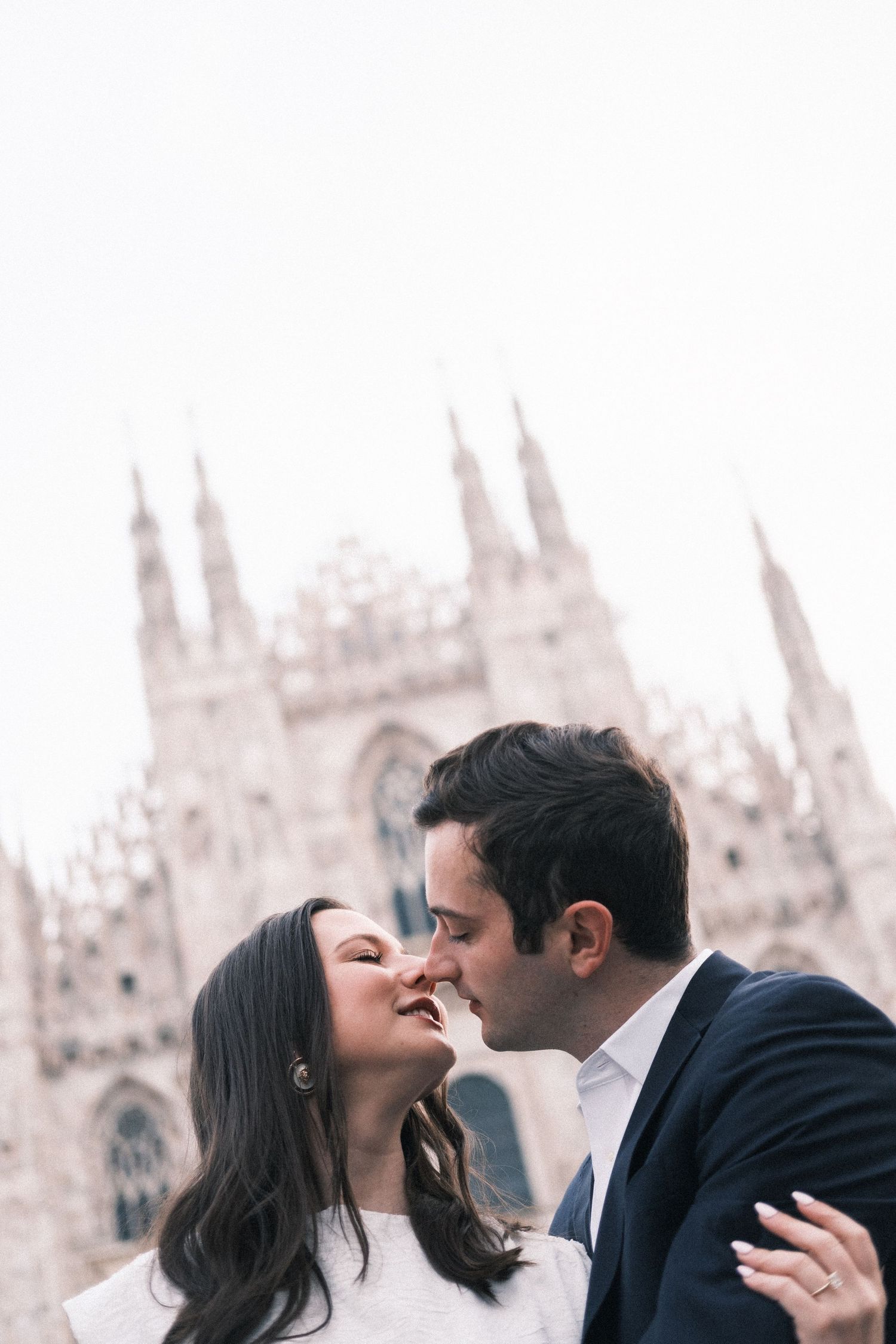 Romantic couple sharing a tender moment in front of the Gothic Milan Cathedral, Duomo di Milano, Italy.