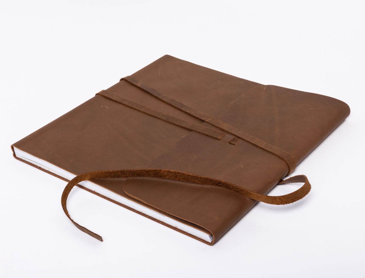 A messenger style photo album with wrap-around tie closure, lying closed on white background.