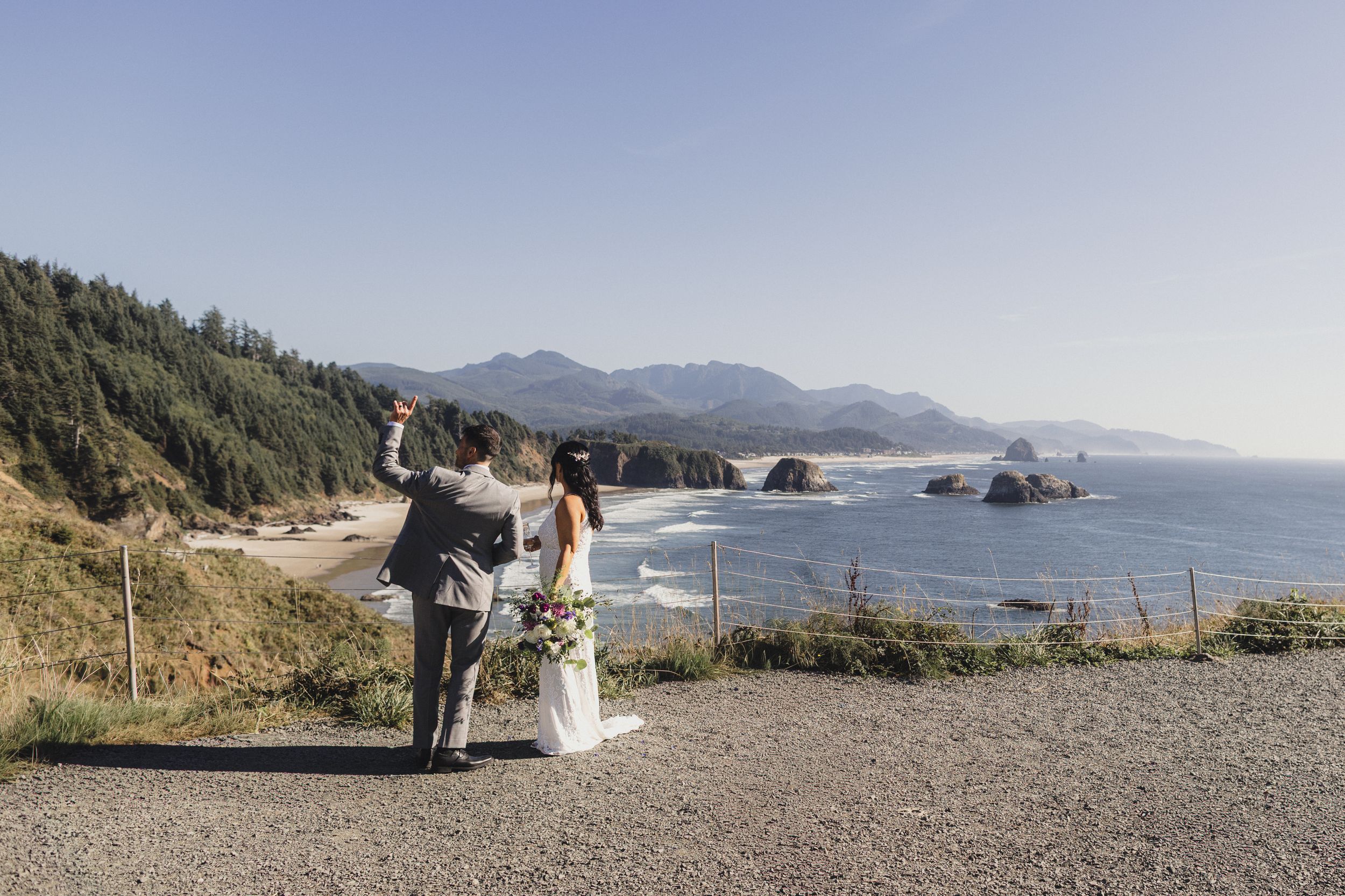 Bride and groom celebrating at scenic Oregon coast overlook.