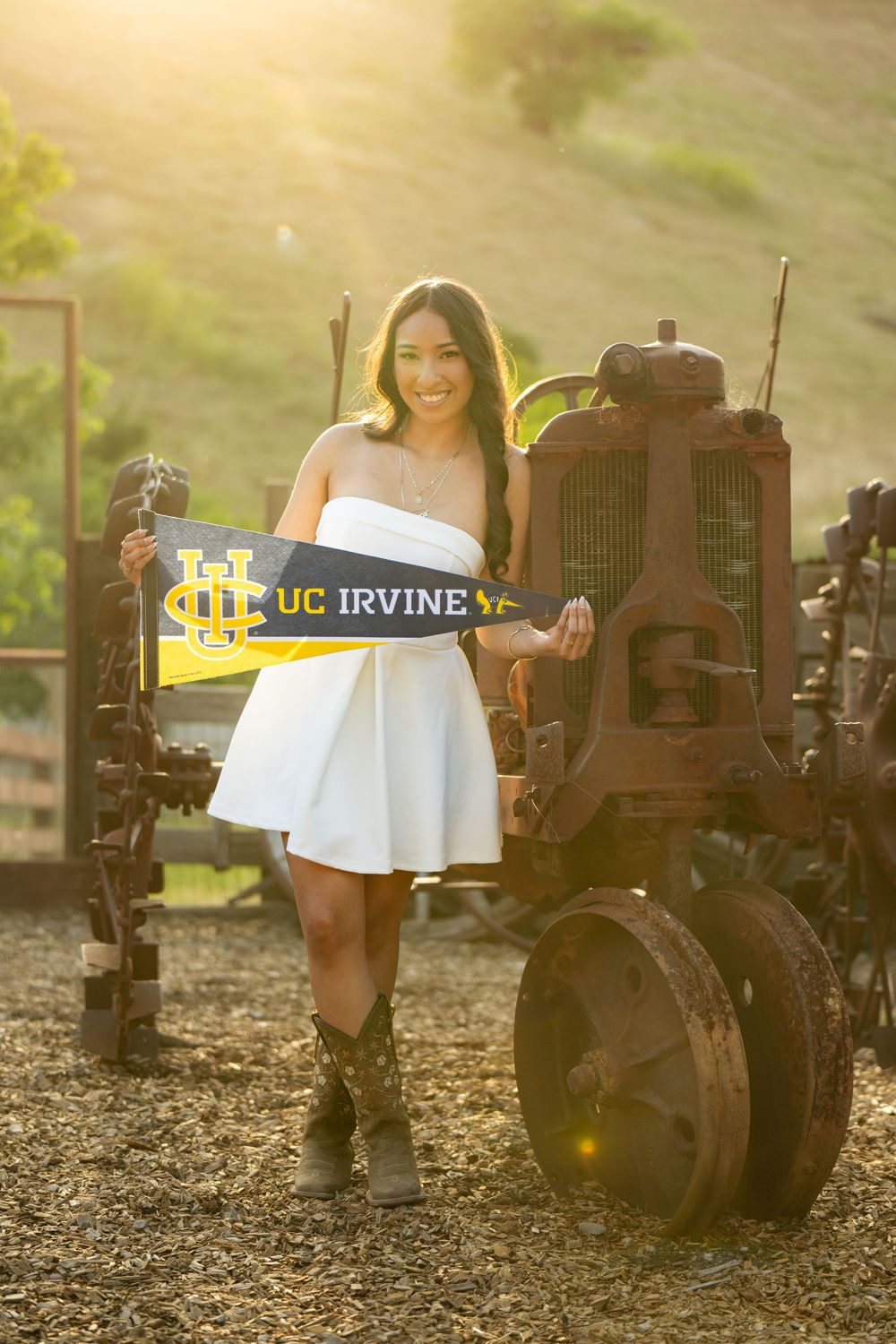 UC Irvine graduate poses with vintage tractor during sunset photo session.