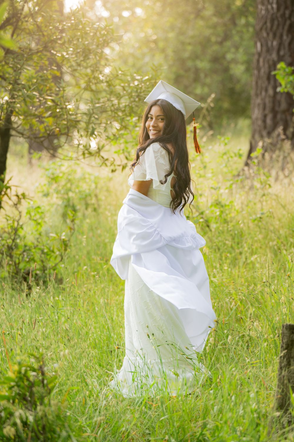 A white dress flows gracefully through a sun-dappled meadow on a warm summer day.