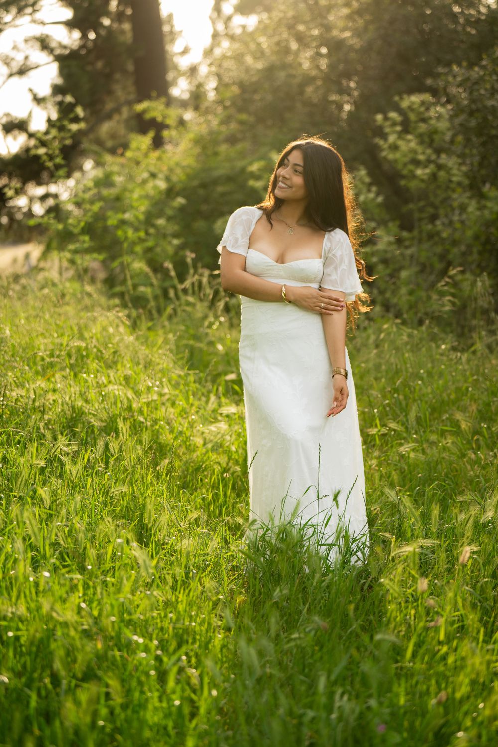 Elegant white dress with cap sleeves photographed in a natural meadow setting.