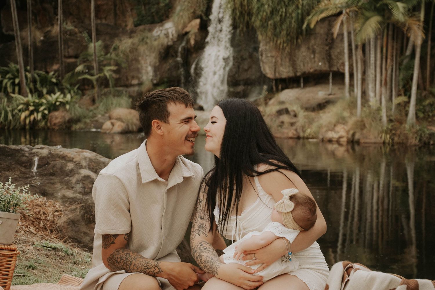 Couple sharing a tender romantic moment while sitting together outdoors near a scenic waterfall.