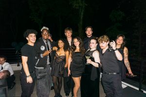 Group of friends in black outfits gather outdoors at a nighttime party.