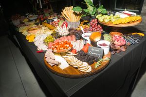 Elegant charcuterie board spread with meats, cheeses, crackers, fruits, and condiments on a dark tablecloth.