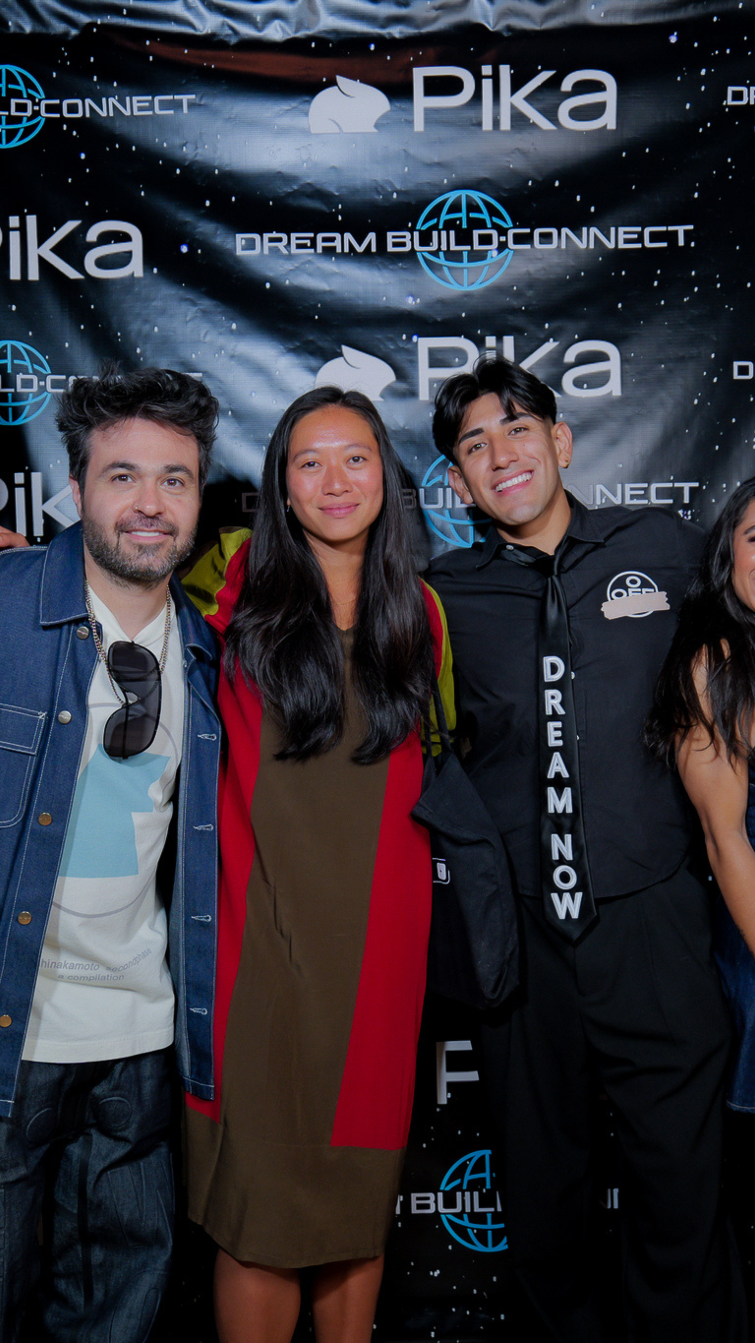 Four people posing together at Dream Build Connect and Pika branded event backdrop.