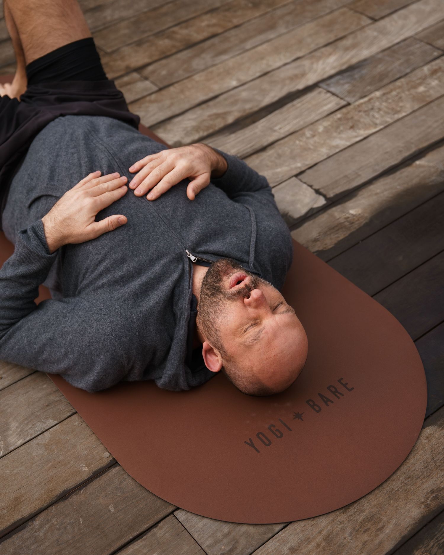 Overhead view of a person lying on a pillow on the floor, wearing a blue shirt with hands crossed on chest.