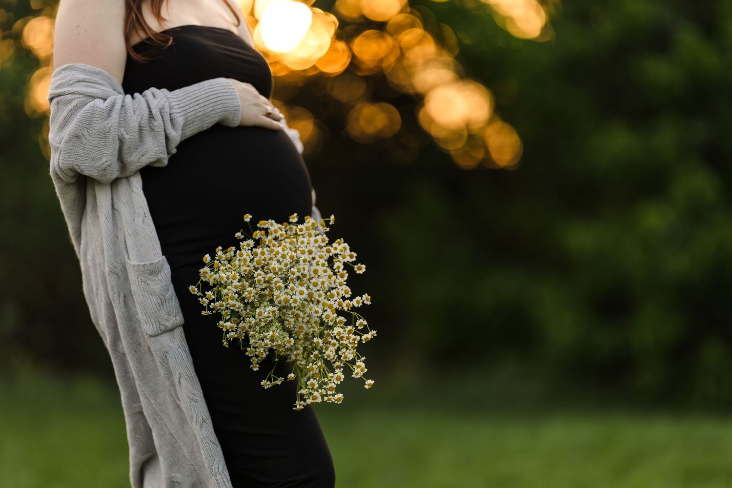 A refined maternity detail shot of a pregnant woman's silhouette in a field, capturing the natural and un-staged beauty of her motherhood jo