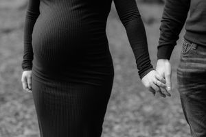A black and white image shows someone wearing a ribbed sweater and jeans while walking outdoors.