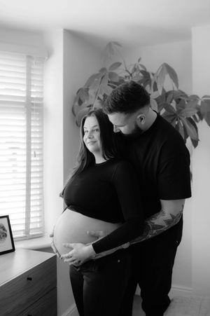 Black and white maternity photo series showing intimate moments between an expectant couple in a bright modern room.