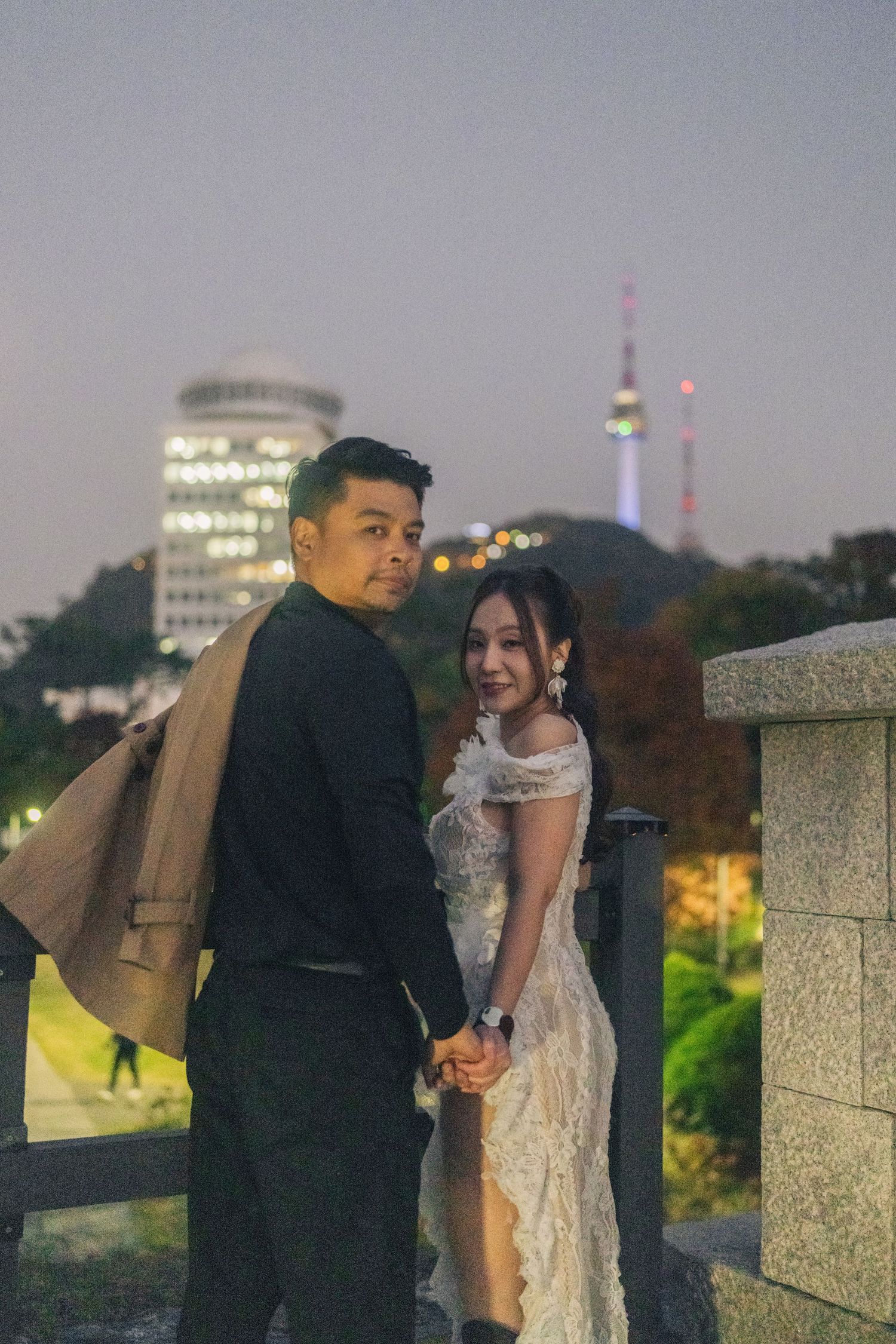 A couple shares a romantic evening moment on a rooftop overlooking a city skyline at dusk.