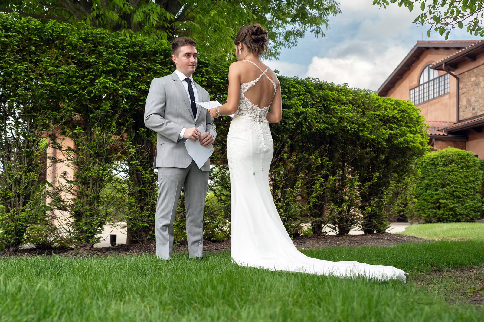 A couple in wedding attire shares romantic moments in a lush green garden setting on their special day.
