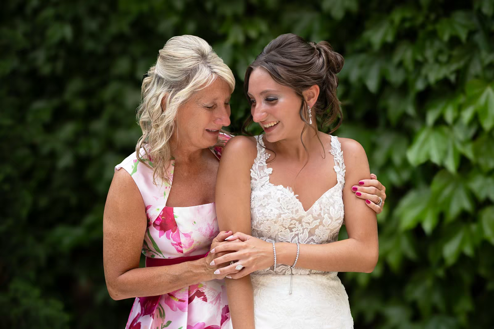 A tender moment shared between two people in wedding attire with lush green foliage in the background.